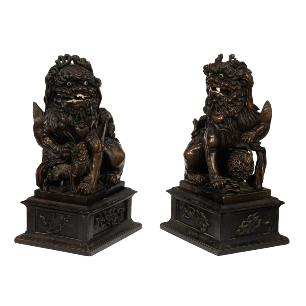 A pair of Chinese rosewood foo dogs: A pair of Chinese rosewood foo dogs. With bulging inset eyes, open mouth revealing teeth and fangs, each raised on a carved rectangular pedestal stand, Republic period, 24.5" high.
