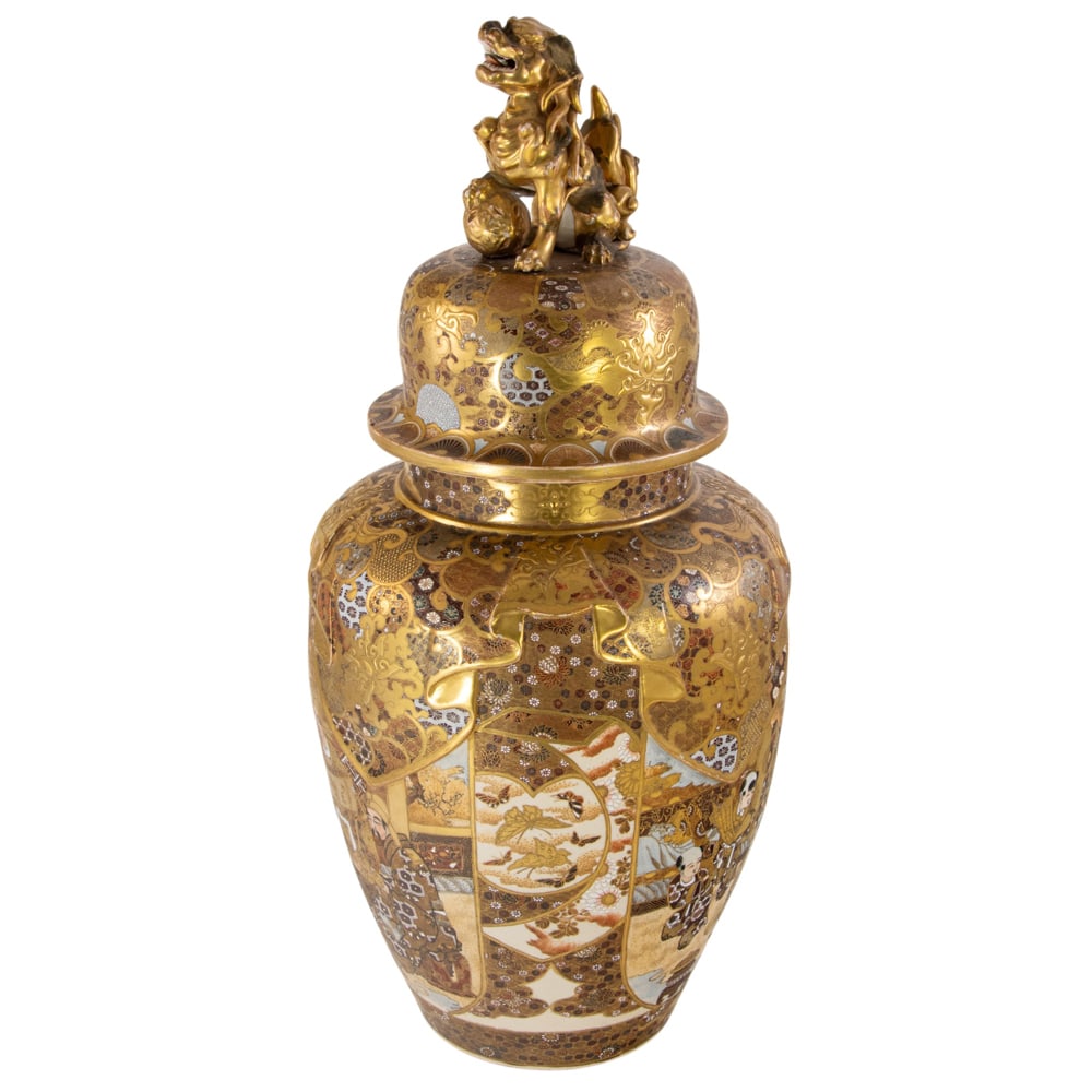 A Japanese Satsuma covered urn: A Japanese Satsuma covered urn. Featuring figural scene surrounded by floral motif, the cover decorated with a gilt shishi finial, Meiji period, 24.625" high. Condition: the finial and the mouth rim