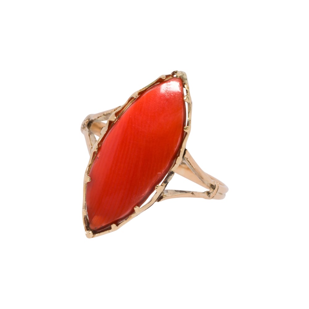 A coral and 18k gold ring: A coral and 18k gold ring centeing a marquis cabochon measuring approximatley 20.00 x 7.20 mm; size: 7; 2.30 grams