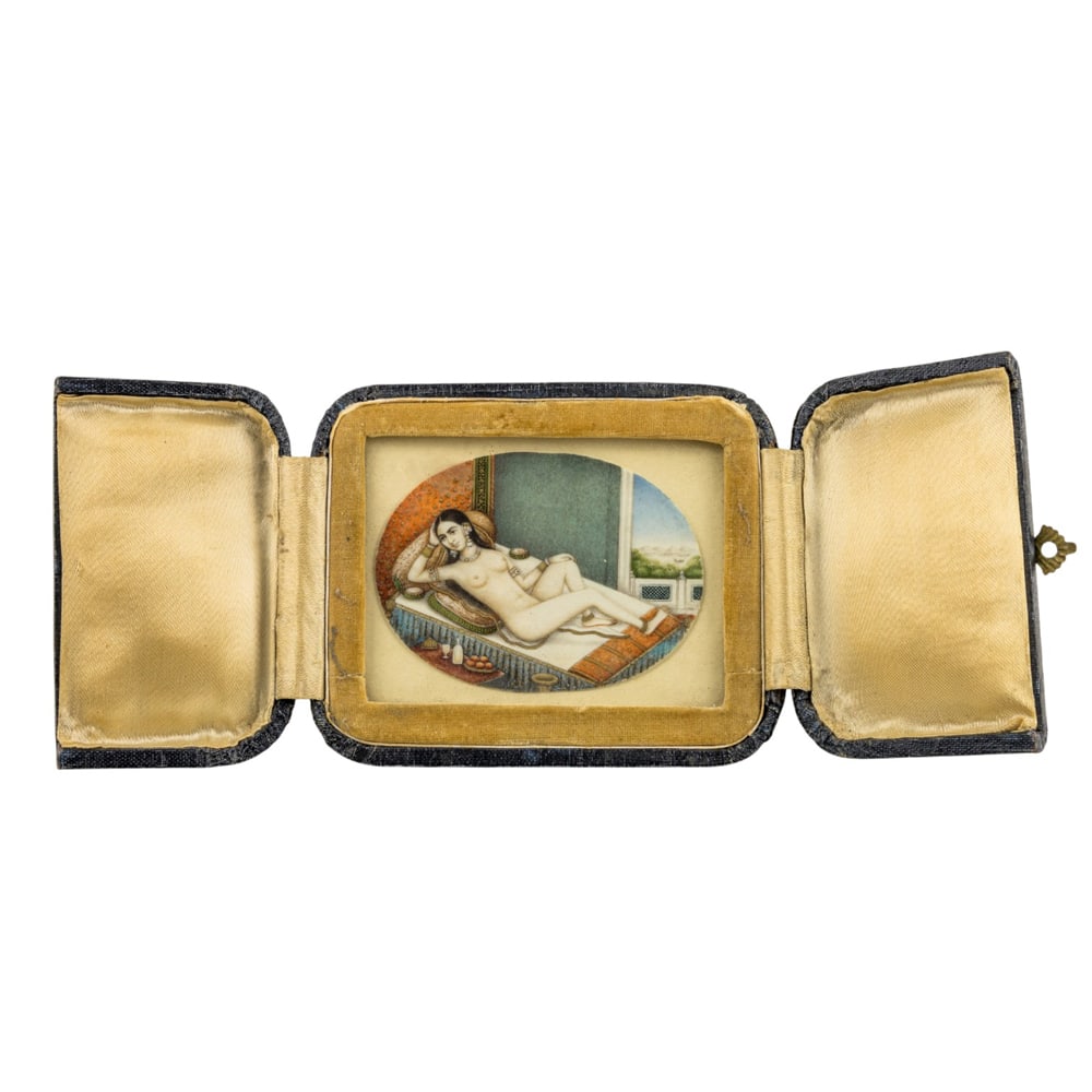 An Indian Mughal erotic subject miniature painting: An Indian Mughal erotic subject miniature painting. Depicting a nude female subject reclining on a bed, 18th/19th century, mounted in a portable picture frame, 2.375"h x 3.375"w.