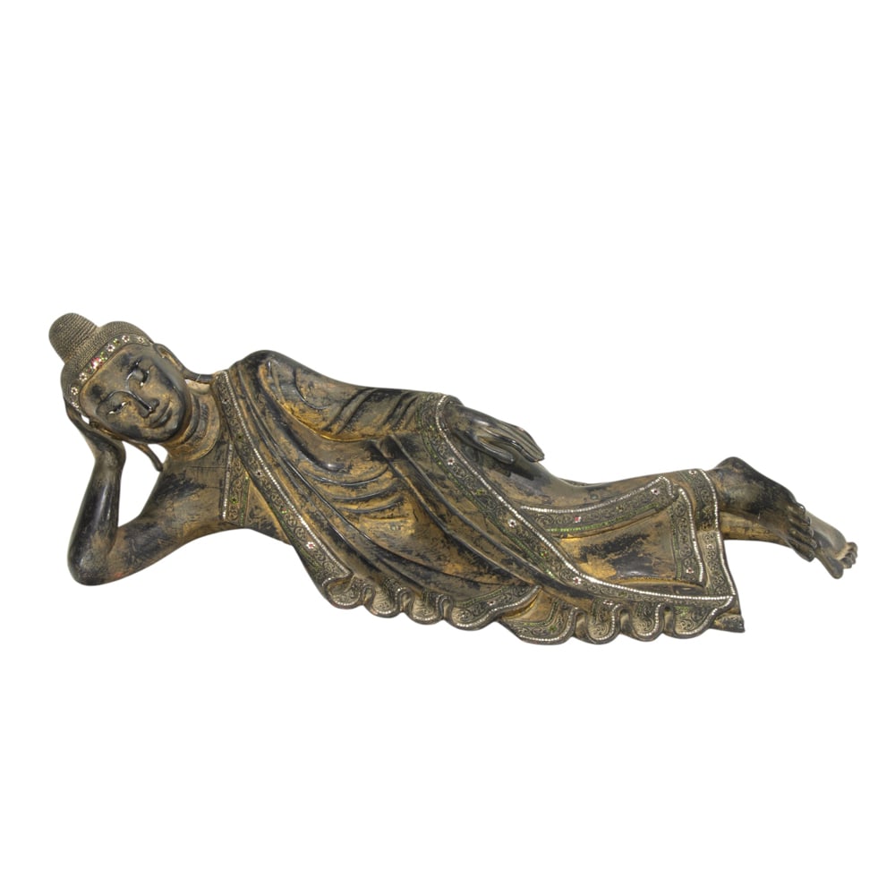 A Burmese lacquered wood of the reclining Buddha: A Burmese lacquered wood of the reclining Buddha. Depicting Buddha in parinirvana, reclining on his right side with the head supported by his right hand, 40" across.