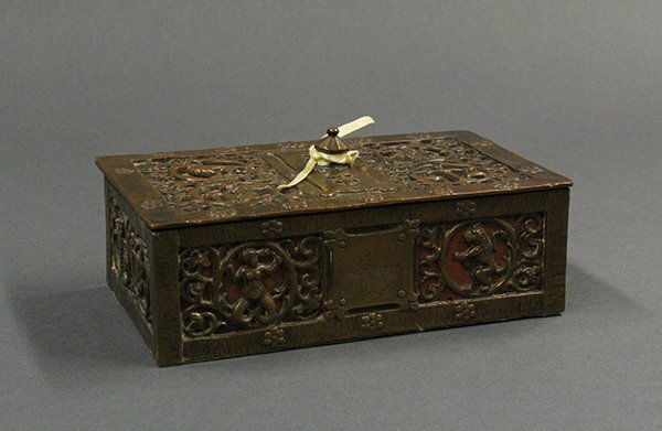 Arts and Crafts mixed metal box: Arts and Crafts mixed metal humidor, having a hinged lid opening to a lined interior and decorated with cut back reserves of zodiac signs on a brick colored ground centering a rectangular shaped knob,