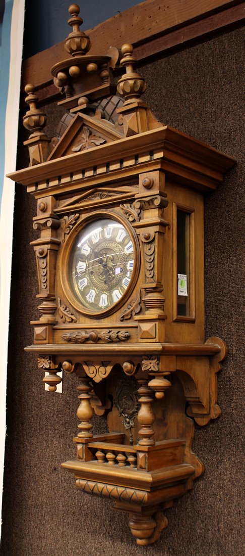 German wall clock: German wall clock, early 20th century, the Renaissance style case with turned finials surmounting the single door opening to the circular dial with enamel decorated Roman markers, the pendulum fronted