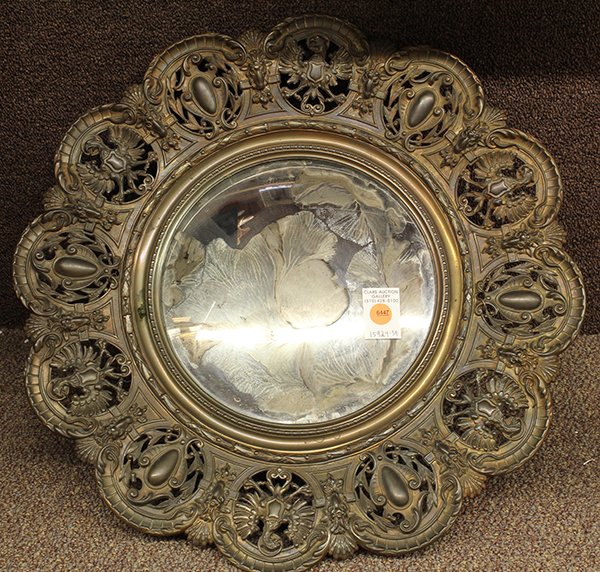 Continental patinated bronze wall mirror: Continental patinated bronze wall mirror, the reticulated frame with alternating Imperial Eagle and shield form reserves surrounding the convex looking glass retaining an eglomise decorated floral spr