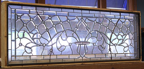 Leaded glass window: Mark Walton, Campbell, CA leaded glass window executed in clear, beveled glass with faceted jewels in a fleur-de-lys design, accented with scrolls and flourishes, having wooden frame with metal braces