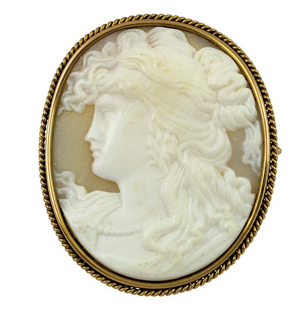 Shell cameo and yellow gold brooch: Shell cameo and yellow gold brooch featuring one oval shell cameo depicting the profile of a classic woman in excellent detail, bezel set in a 14K yellow gold twisted wire frame. Approximately 2 X 1 1