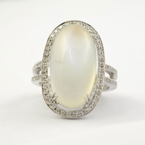 Moonstone diamond white gold ring: Moonstone, diamond and 18K white gold ring featuring (1) oval-cut moonstone cabochon measuring 19.8 x 10.9 x 9.04 mm, accented around by diamonds totaling approximately 0.44 ct; 8.4 grams; Size 7