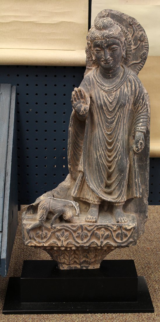 Gandharan-style Figure of the Buddha: Gandharan style stone Buddhist figure, with the historical Buddha and a kneeling Mara about to cut her hair, the tapering base accented with leafy tendrils, with a black stand, overall: 27.75"h