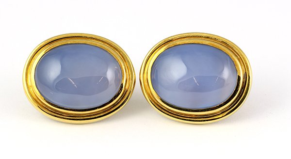 Blue chalcedony yellow gold earrings: Pair of blue chalcedony and 18K yellow gold earrings each oval mounting is bezel set with an oval cabochon blue chalcedony measuring approximately 12.10 x 14.15 mm; 24.5 grams