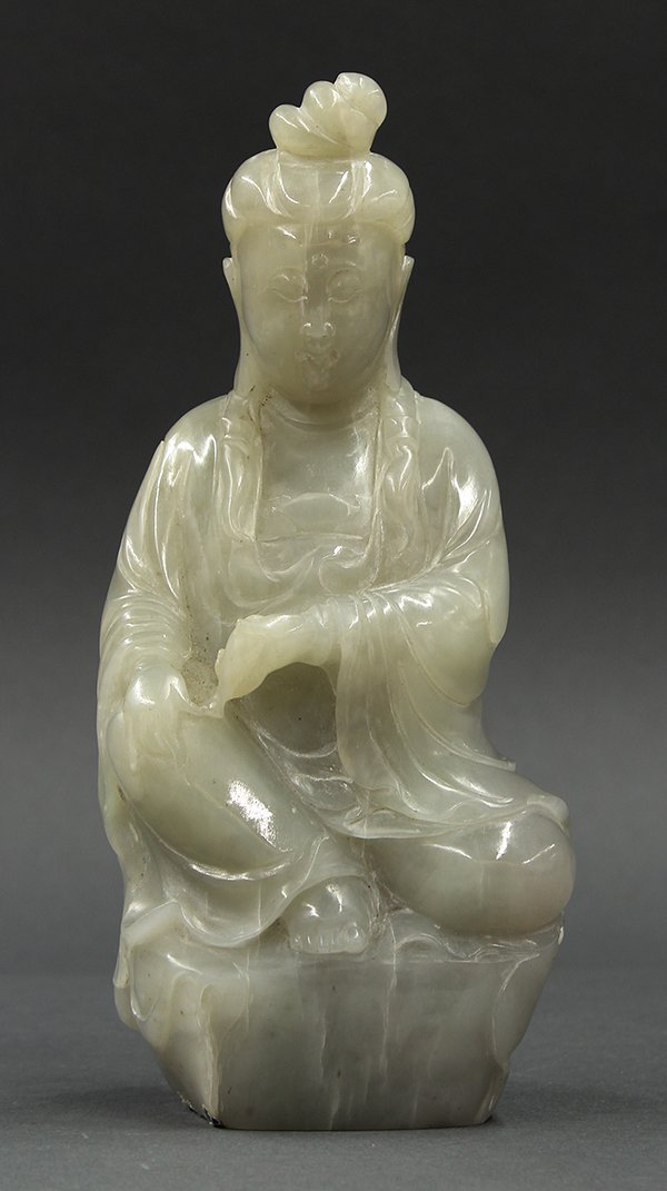 Chinese Jade Guanyin: Chinese jade figural carving, of Guanyin seated in royal ease on a plinth, carved with a serene face and holding a vase in the left hand, the gray-green matrix with light striations and dark flecks, 7