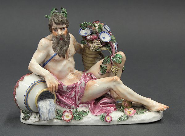Continental porcelain figural group: Continental porcelain figural group, depicting a partially nude Bacchus holding a bountiful cornucopia, leaning against a flowing amphora, and rising on a naturalistic base, unmarked, 5.5"h x 8"w (los