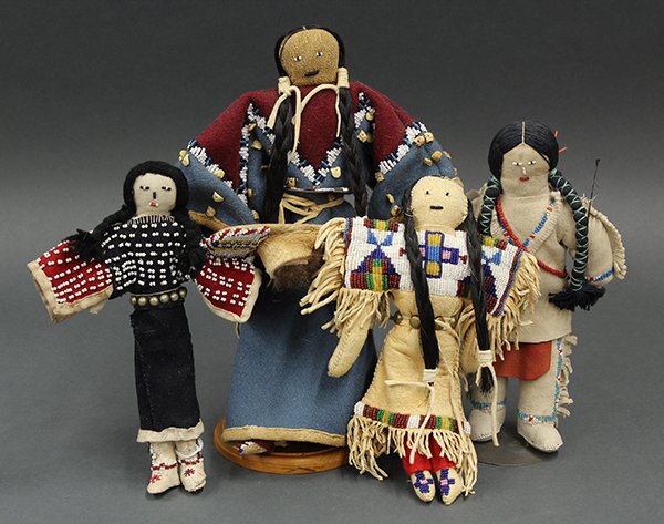 Native American dolls, two having beaded native tanned: (lot of 4) Native American dolls, two having beaded native tanned hide outfits; together with one having a fabric dress and another carrying a beaded cradle board, 12"h.Provenance: Property from the c