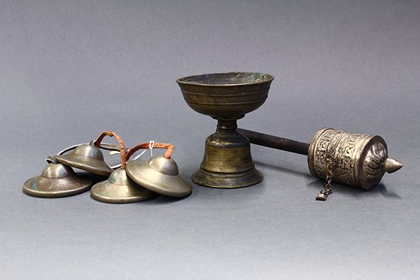 Himalayan Buddhist Items: (lot of 4) Himalayan Buddhist ritual items, consisting of two pairs of cymbals; a footed bronze bowl raised on a pedestal base; together with a repousse prayer wheel, 9.5"h