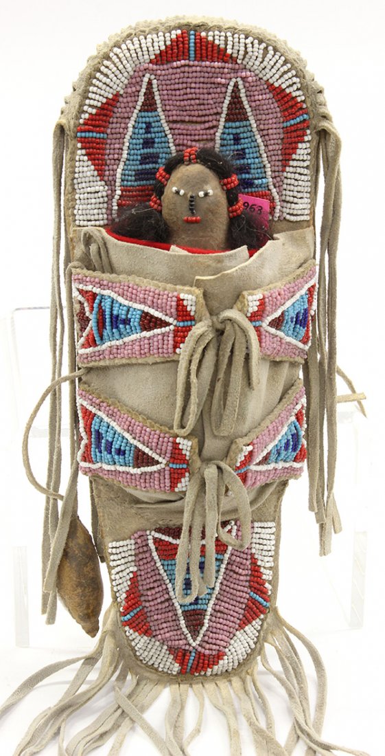 Hopi beaded child's doll and back board cradle: Hopi beaded child's doll and back board cradle executed in tanned leather with multi-colored beads and fetish, retaining old pawn tag; 16"l including fringe