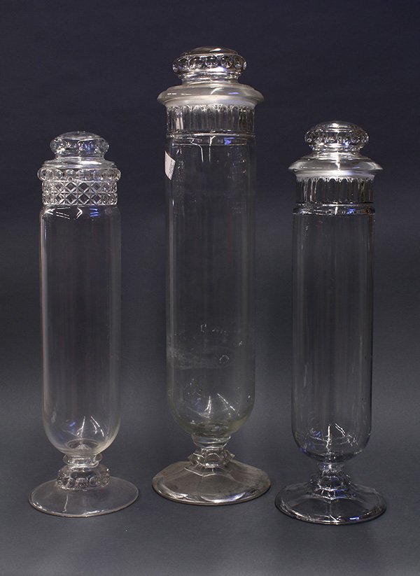 Antique style candy jars: (lot of 3) Victorian style candy jars, executed in molded glass and having ground lids, above cylinder form bodies, and resting on circular feet, tallest, 28.5"h., (one lid replaced).