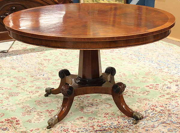 Regency mahogany dining table: Regency mahogany dining table, 19th century, the circular top wit banding surmounting the octagonal standard continuing to the lower tier, and rising on outswept feet terminating on brass capped caste