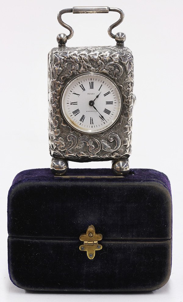 English Victorian sterling silver cased carriage clock: Victorian carriage clock, by Rossi Norwich, having an enameled face with Roman markers, mounted in an English sterling silver floral repousse case opening to a gilt interior, rising on four ball feet,