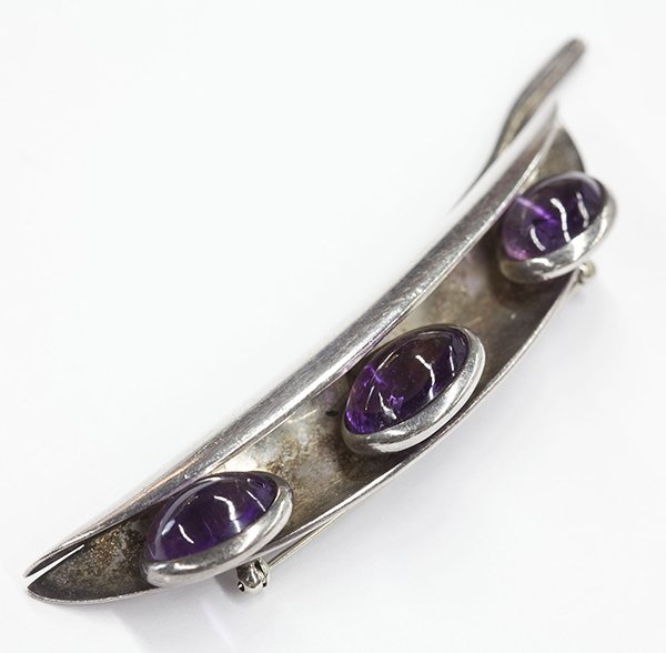 Antonio Pineda amethyst silver brooch: Antonio Pineda amethyst and sterling silver brooch set with (3) oval cabochon amethysts measuring approximately 15 x 12 mm and 13 x 10 mm, set in a bean pod brooch, signed with Pineda mark, eagle qual