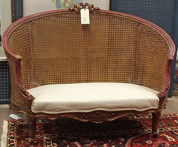 Neoclassical style partial giltwood settee: Neoclassical style partial giltwood settee, the carved floral crest above the cane back, continuing to the cream upholstered seat, and rising on cabriole legs, 36"h x 42"w x 22.5"d