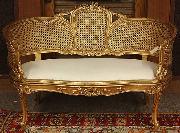 Louis XV style giltwood carved settee: Louis XV style giltwood carved settee, the contoured back centered with a carved crest surmounting the cane panels, having a serpentine seat and rising on cabriole legs, 33"h x 50"w x 24"d