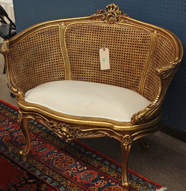 Rococo style giltwood settee: Rococo style giltwood settee, having a carved floral crest centering the curved cane back continuing to the inswept acanthus decorated arms, and rising on outswept legs, 36"h x 32"w x 18"d