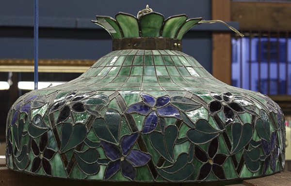 Arts and Crafts stained glass hanging fixture: Arts and Crafts stained glass hanging fixture, having a three socket cluster surmounted by the geometric decorated shade accented with a floral decorated frieze, 14"h x 24"w