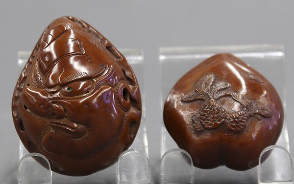 Two Japanese Walnut Lacquered Netsuke: (lot of 2) Japanese netsuke, one in the shape of a walnut carved with Tengu, marked with signature 'Saichizan'; one of plum pit shape with a shuro and snail, largest 1.75"l
