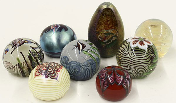 Art glass paperweights: (lot of 8) Art glass paperweights including a Zellique egg form with an iridescent purple exterior surrounding the clear reserve showing a butterfly over flowers; together with hand painted and cased