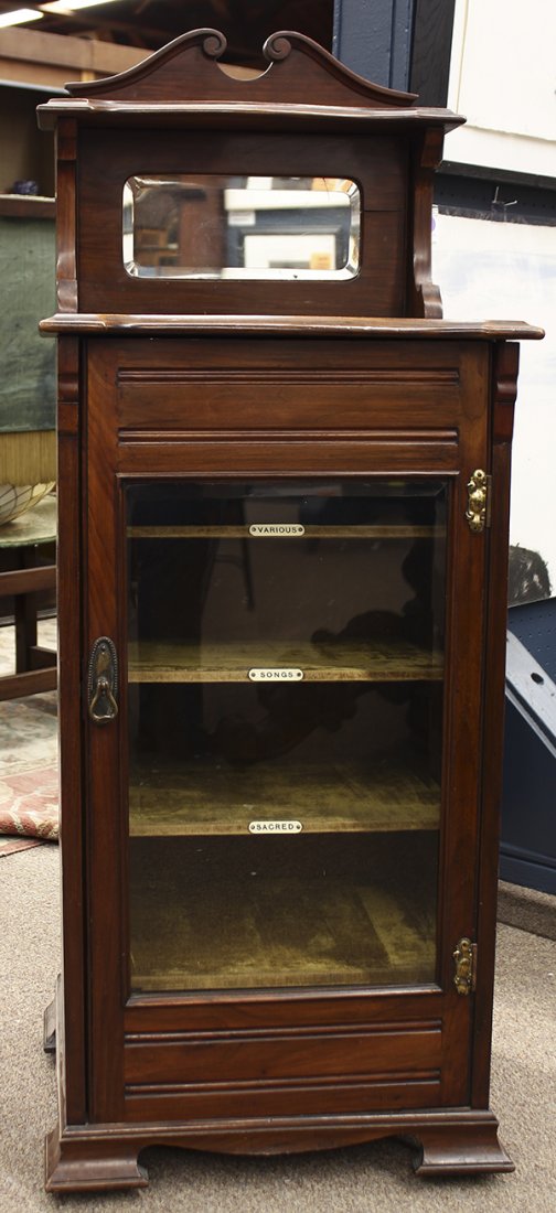 Edwardian music cabinet: Edwardian music cabinet, circa 1900, executed in walnut with a broken scroll pediment surmounting a small shelf, above a backsplash with a mirror, having one door with a beveled glass leading to three