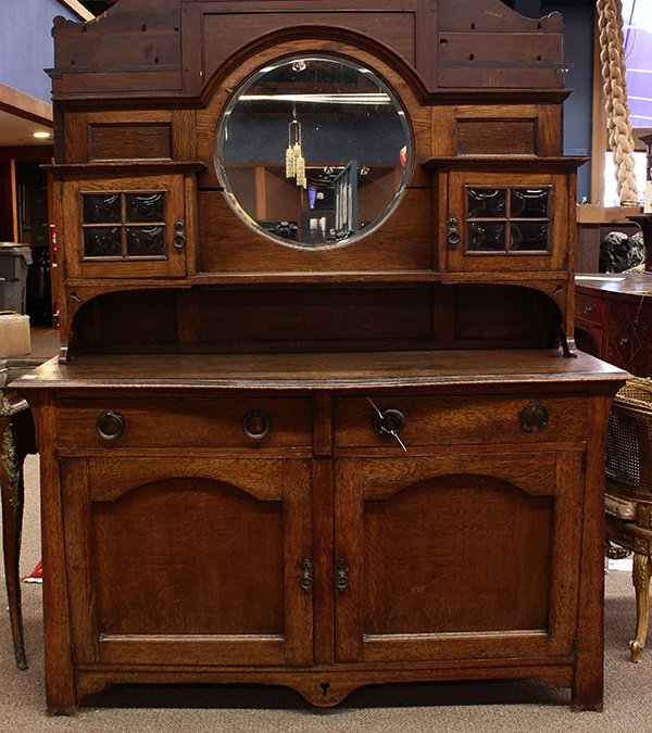 English Arts and Crafts sideboard: English Arts and Crafts sideboard, executed in quartersawn oak circa 1910, the superstructure having a bevelled mirror back flanked by two glass doors, surmounting the lower case retaining the origina