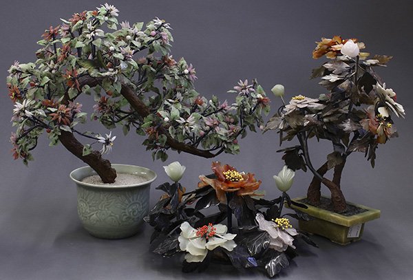 Three Chinese 'Jade' Trees: (lot of 3) Chinese hardstone and glass plants, consisting of a glass tree with pink and coral flowers in a celadon pot; two hardstone and jade plants with peony blossoms; largest 20.5"h