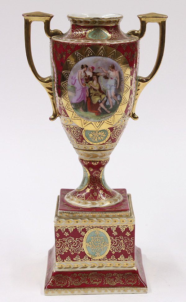 Royal Vienna porcelain urn: Royal Vienna porcelain urn, of Classical form, with gilt handles having a scenic reserve depicting maidens surrounding a youth, signed Kaufmann, with scattered gilt accents on a raspberry ground, the