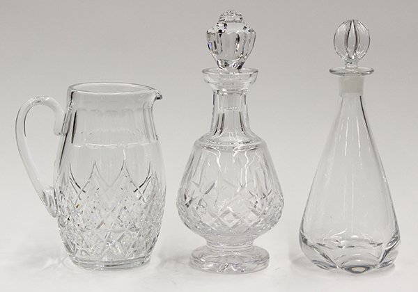 Crystal group: (lot of 3) Crystal group, consisting of an Orrefors crystal decanter having a spherical stopper surmounting the tear drop base, a Waterford crystal decanter, and a Baccarat crystal pitcher having a cu