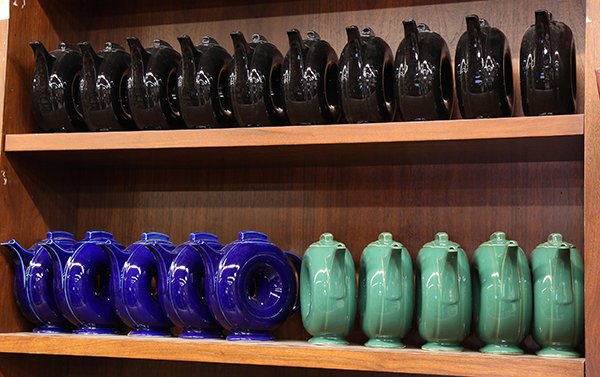 Two shelves of Hall 'Donut' teapots: (lot of 20) Two shelves of Hall 'Donut' teapots, after the 1938 originals, are glazed in black, cobalt, and emerald green, marked 'Made especially for Naomi's of San Francisco 1993, Hall Made in USA',