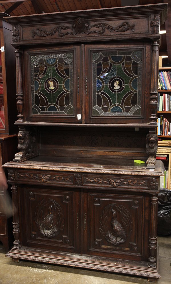 Renaissance Revival oak court cupboard, late 19th: Renaissance Revival oak court cupboard, late 19th century, in two parts, having a molded cornice above a freize with applied mounts, surmounting a cabinet with two leaded glass doors having central ov