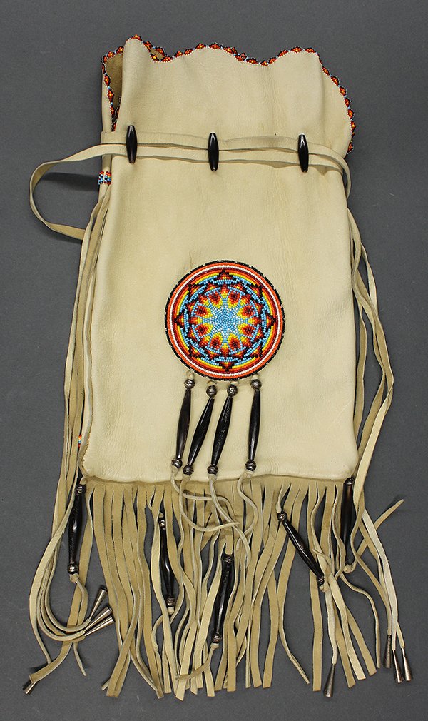 Native American, handmade leather shoulder bag: Native American, handmade leather shoulder bag, one side having a circular beadwork medallion, verso with silvered metal decoration terminating at the fringed base, 12.5"h overall
