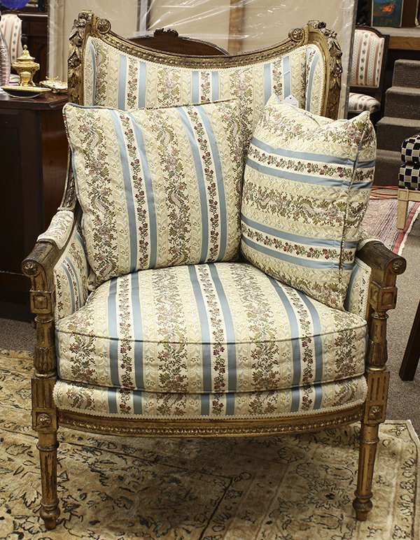 Louis XVI style giltwood bergere: Louis XVI style giltwood bergere, the shaped back framed with carved rosettes and floral sprays continuing to the outswept returns, centering the upholstered seat, and rising on fluted and turned legs