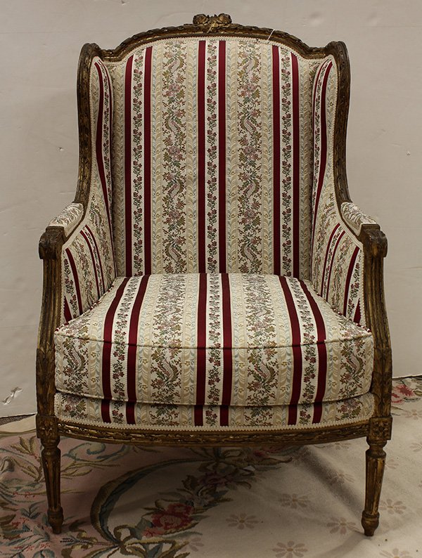 Louis XVI style giltwood bergere: Louis XVI style giltwood bergere, circa 1900, the shaped back having a floral carved crest, continuing to the acanthus carved returns, centering the upholstered seat, and rising on fluted and turned l