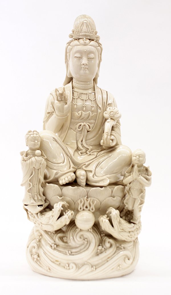 Chinese Blanc de Chine Guanyin: Chinese Dehua porcelain figure, featuring Guanyin holding a ruyi scepter and seated on a lotus pedestal, flanked by a pair of attendants supported by dragons, 20"h