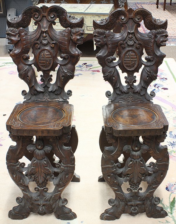 Pair of Continental Renaissance style hall chairs: Pair of Continental Renaissance style hall chairs, second half 19th century, executed in walnut, each having a carved crest continuing to the figural seat back depicting the North Wind, above a circul