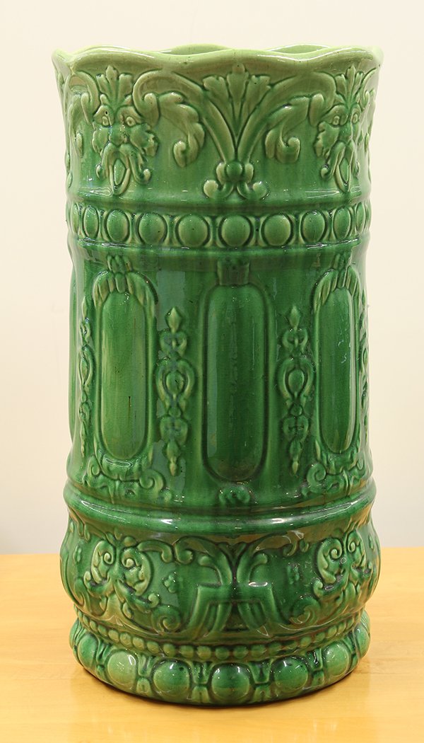 American art pottery umbrella holder: American art pottery umbrella holder, late 19th century, having a green glaze covering the relief decorated body accented with figural medallions, 20" x 10.5"