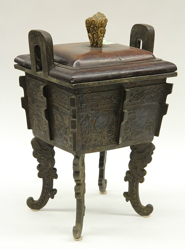 Chinese Large Bronze Ding: Chinese rectangular bronze ding, the body cast with taotie masks accented notched flanges, raised on scrolling zoomorphic supports, together with a wood lid, 17.25"h