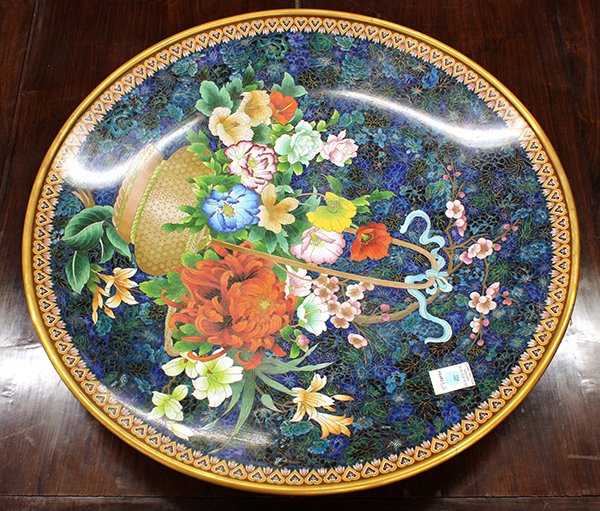 Chinese Cloisonne Charger: Chinese cloisonne enameled charger, featuring a flower basket with peonies, prunus and lilies on a blue-green mille fleur ground, 25.75"w. Provenance: From the estate of Edward Gerber