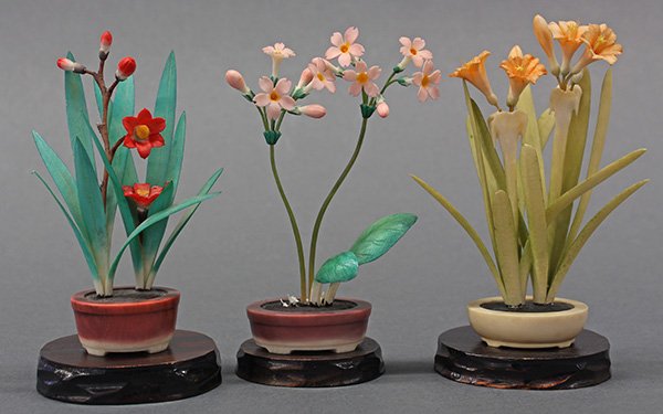(lot of 3) Miniature Japanese polychrome carved ivory: (lot of 3) Miniature Japanese polychrome carved ivory flowers, including lilies, each in a miniature pot and resting on a wooden stand, 4.5"h