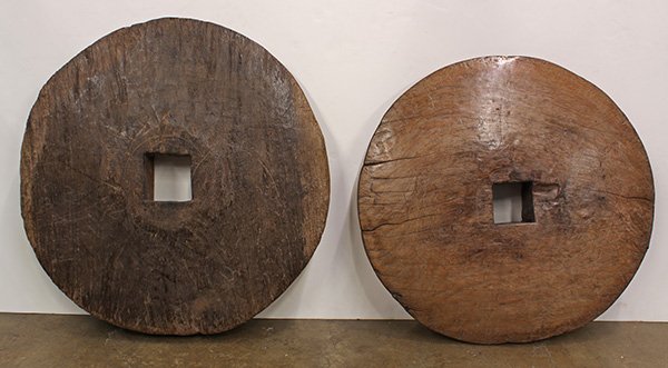 Indonesian shaped driftwood wheels, 19th century: (lot of 2) Indonesian shaped driftwood wheels, 19th century, each disc form having a honed surface centered with a square holes, probably used for carts, largest: 28"