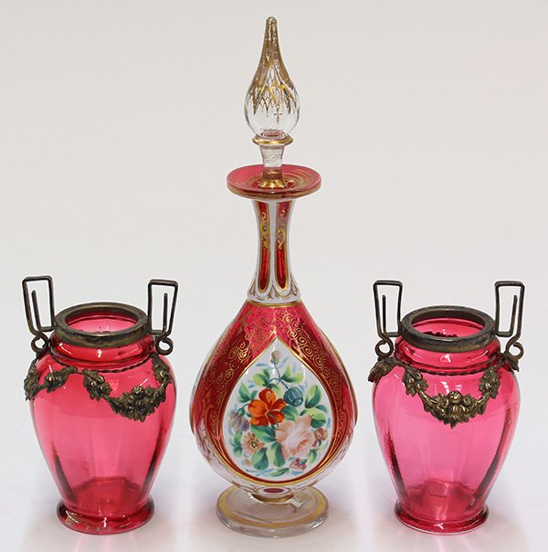 Bohemian cranberry glass dresser items: (lot of 3) Bohemian cranberry glass dresser items, consisting of a stoppered perfume bottle having a tear drop form, executed in white to cranberry glass, and having scrolling gilt accents surrounding