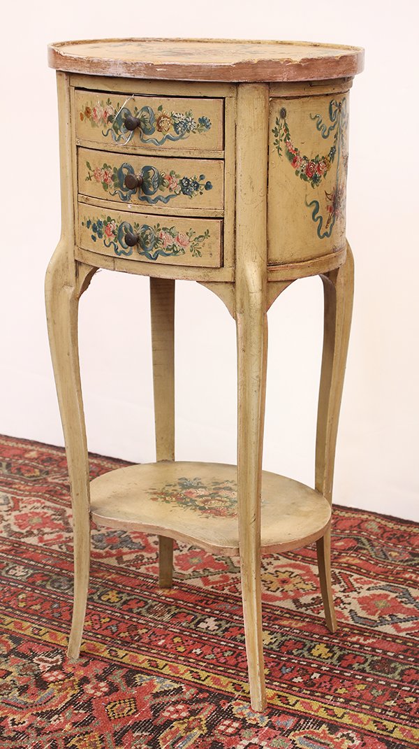 Italian paint decorated commode: Italian paint decorated commode, third quarter 19th century, the oval top centered with an floral and ribbon medallion surmounting the three drawer case, the sides with garland swags, and rising on ca