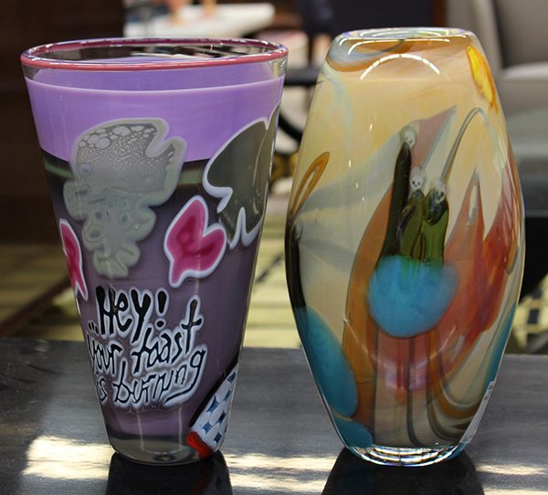 (lot of 2) Art glass group in the Moderne taste, circa: (lot of 2) Art glass group in the Moderne taste, circa 1981, consisting of a Rick Berstein, tapered vase, executed in lavender and grey glass, having a surrealist scene and the motto 'Hey! Your Toast 