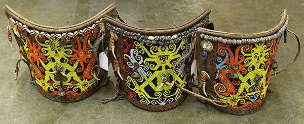 (lot of 3) Indonesian tribal baby carriers, executed in: (lot of 3) Indonesian tribal baby carriers, executed in beaded basketry, possibly Dayak, each of demilune form with an intricately beaded panel depicting mythological beings, trimed with cowrie shells
