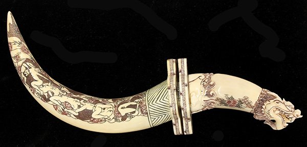 Japanese erotic carving in the form of a curved dagger: Japanese erotic carving in the form of a curved dagger, having incised polychrome decoration, the figural dragon hilt with a demon at the tuba, surmounts a sheath incised with a peaceful landscape on 